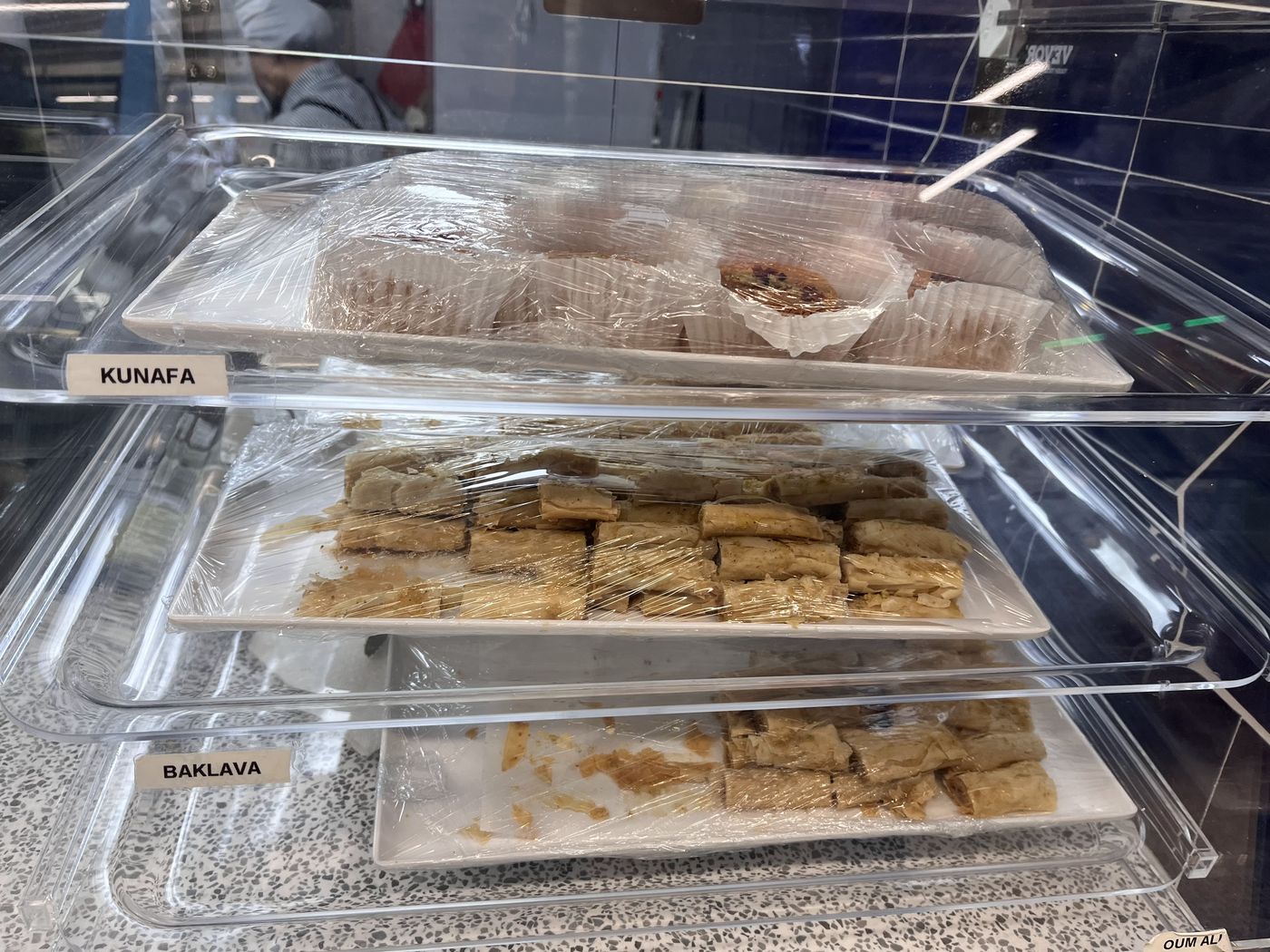 The dessert case with kunafa and baklava trays